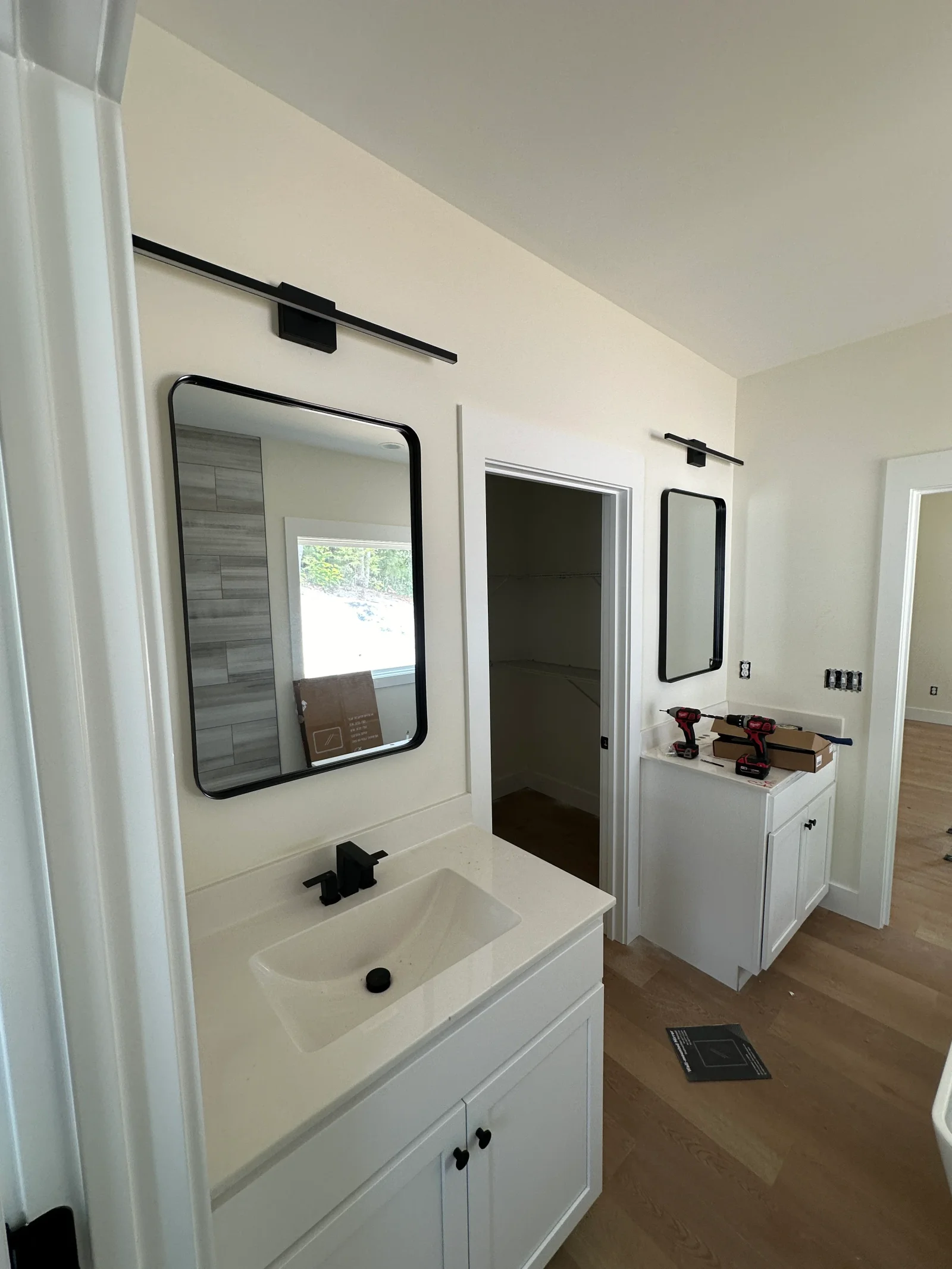 White shaker vanity with integrated sink, black framed mirror, and black linear wall light in a newly finished bathroom