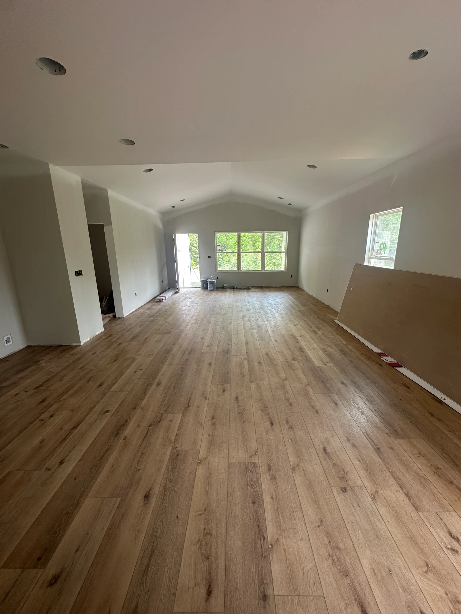 Vaulted living room with wide-plank oak-look luxury vinyl flooring, recessed lighting, and white painted drywall